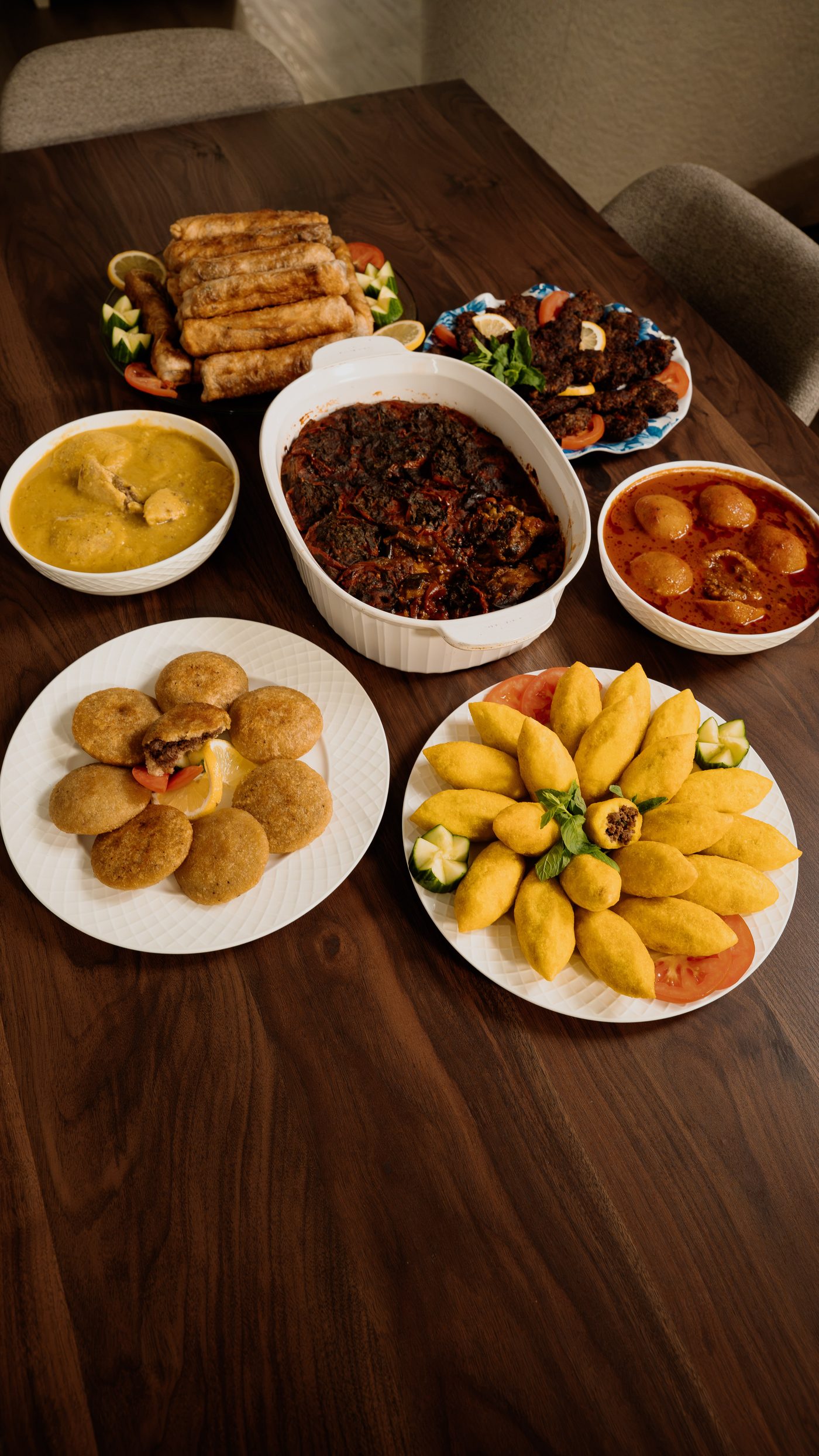 An Iraqi table set with kubba, bourak, kabab arooq and bowls of stew on a walnut surface