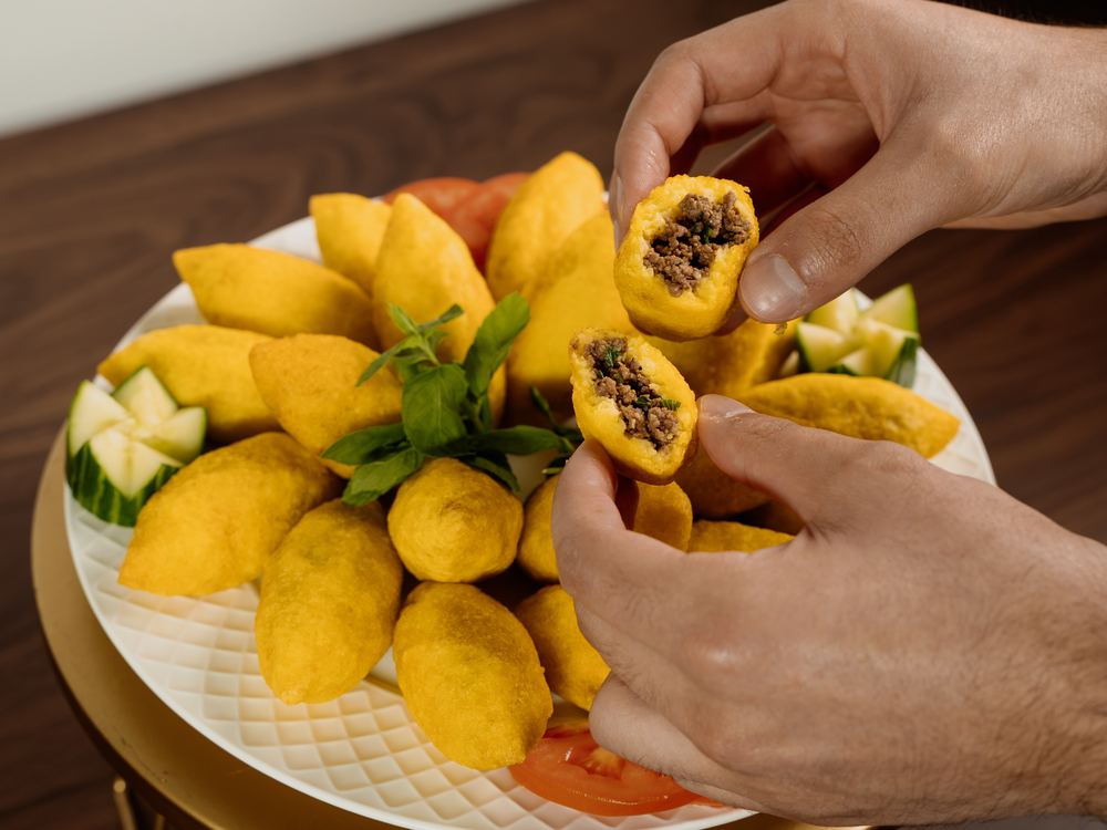 Hands breaking open a Kubba Halab to show the filling