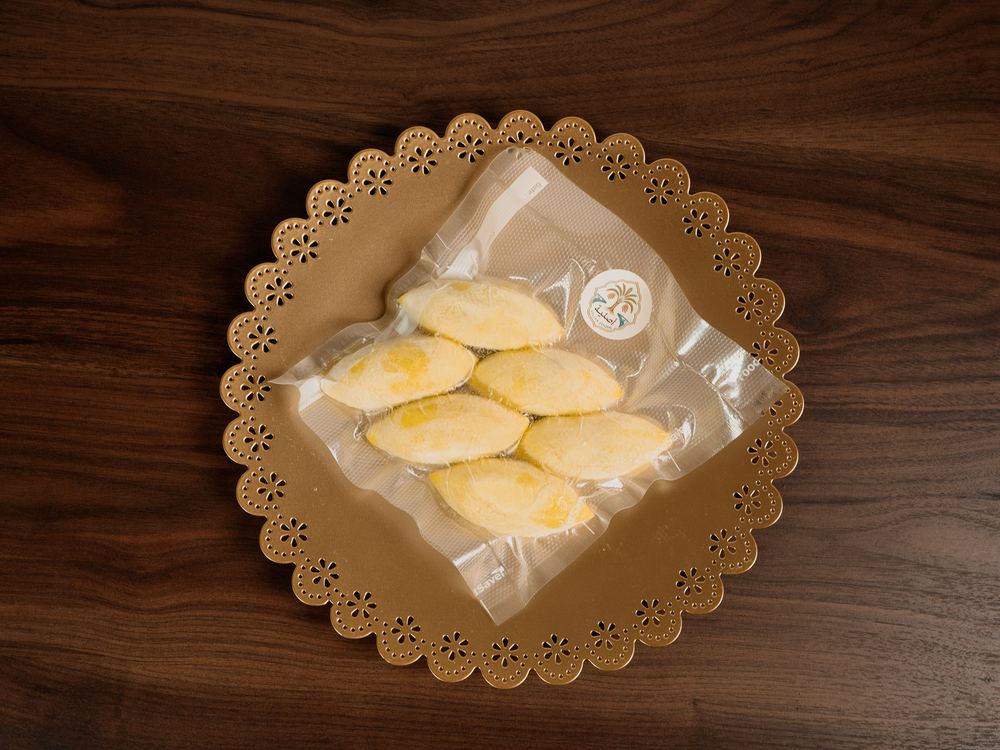 A sealed pack of frozen Kubba Halab on a walnut table