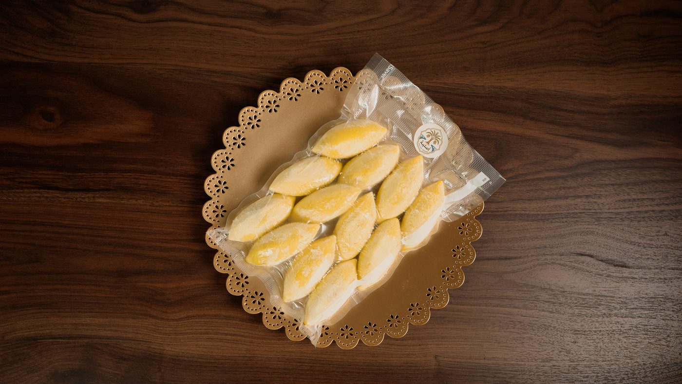 A sealed pack of frozen Kubba Halab beside a finished plate of the same dish