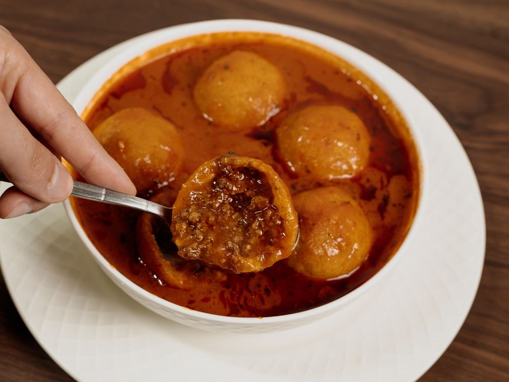 A spoon lifting a Kubba Saray dumpling from the broth