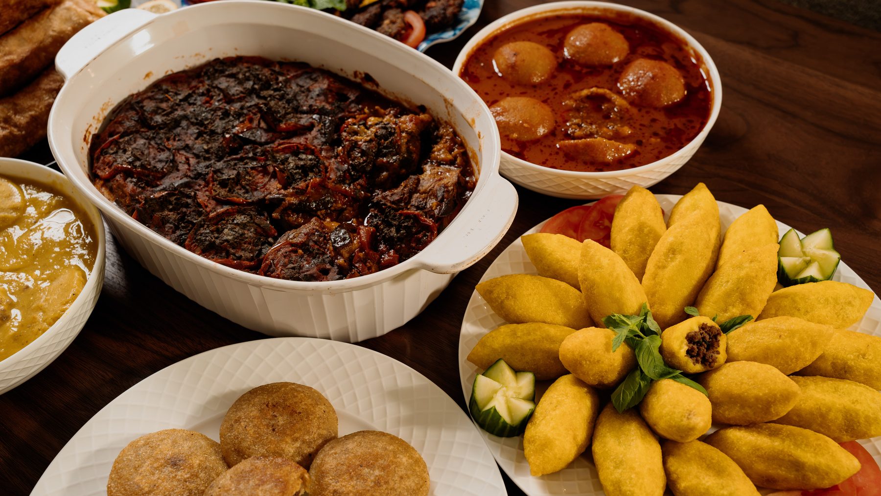 An Iraqi family spread of kubba, bourak, kabab arooq and stews laid across a walnut table